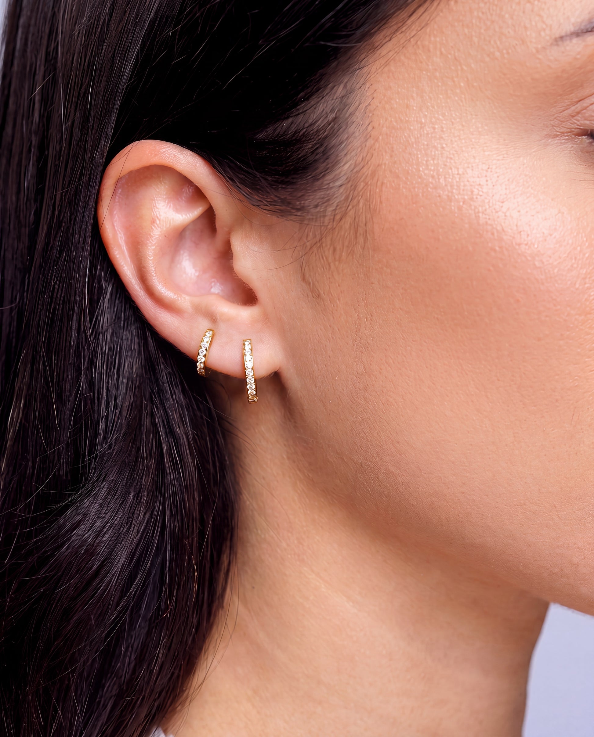 Olivia Classic Gold titanium huggie hoop earrings worn in ear — 18K gold PVD, non-touch coating for sensitive ears